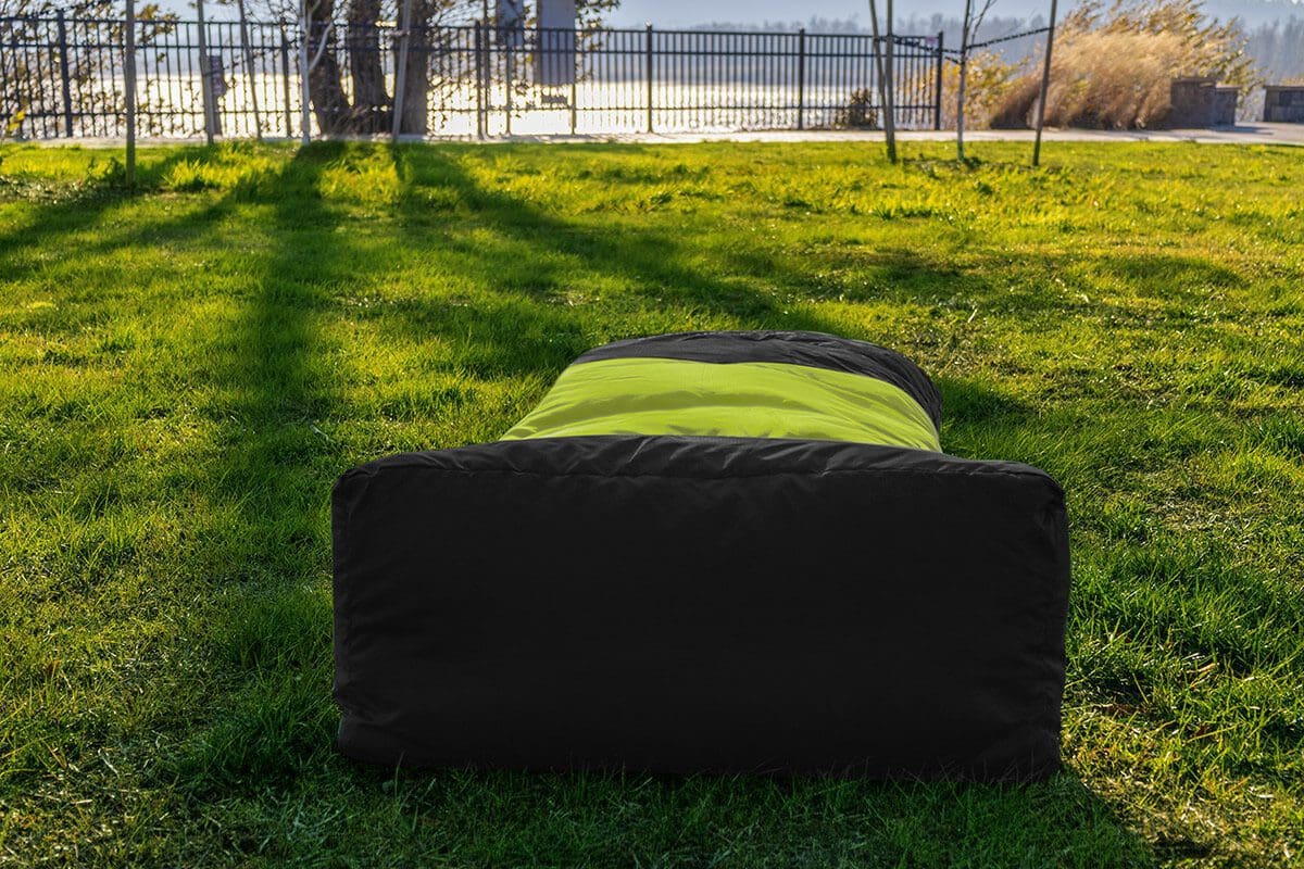 A black and green dog bed in the grass.