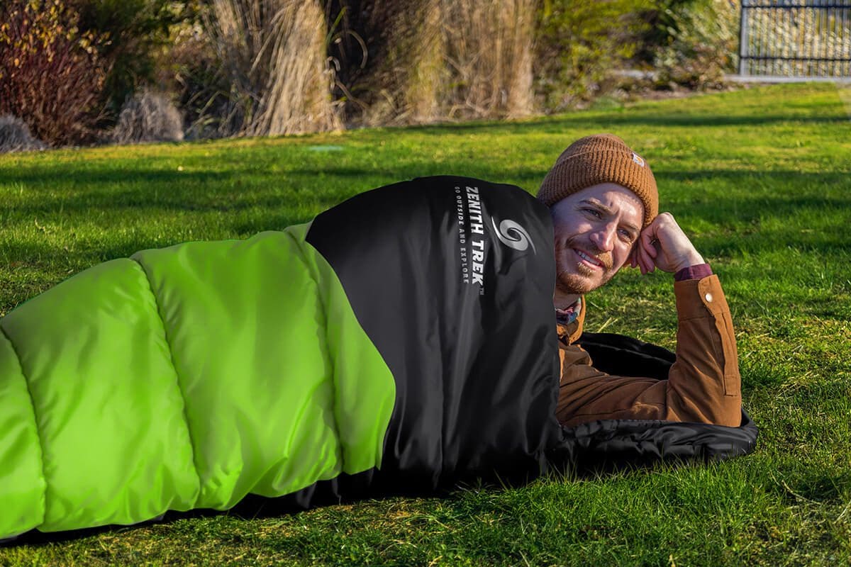 A man laying on the ground in a sleeping bag.