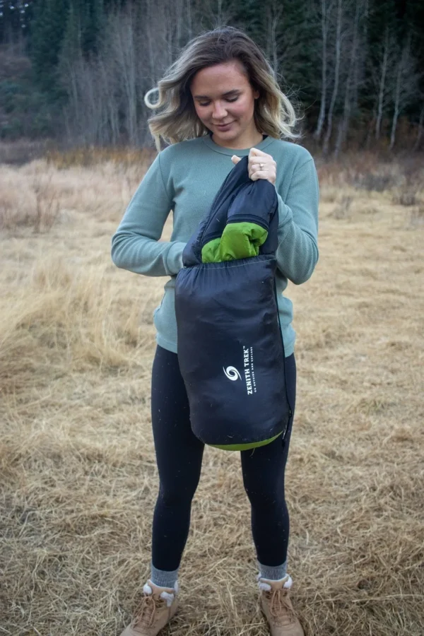 A woman holding onto a bag in the grass.